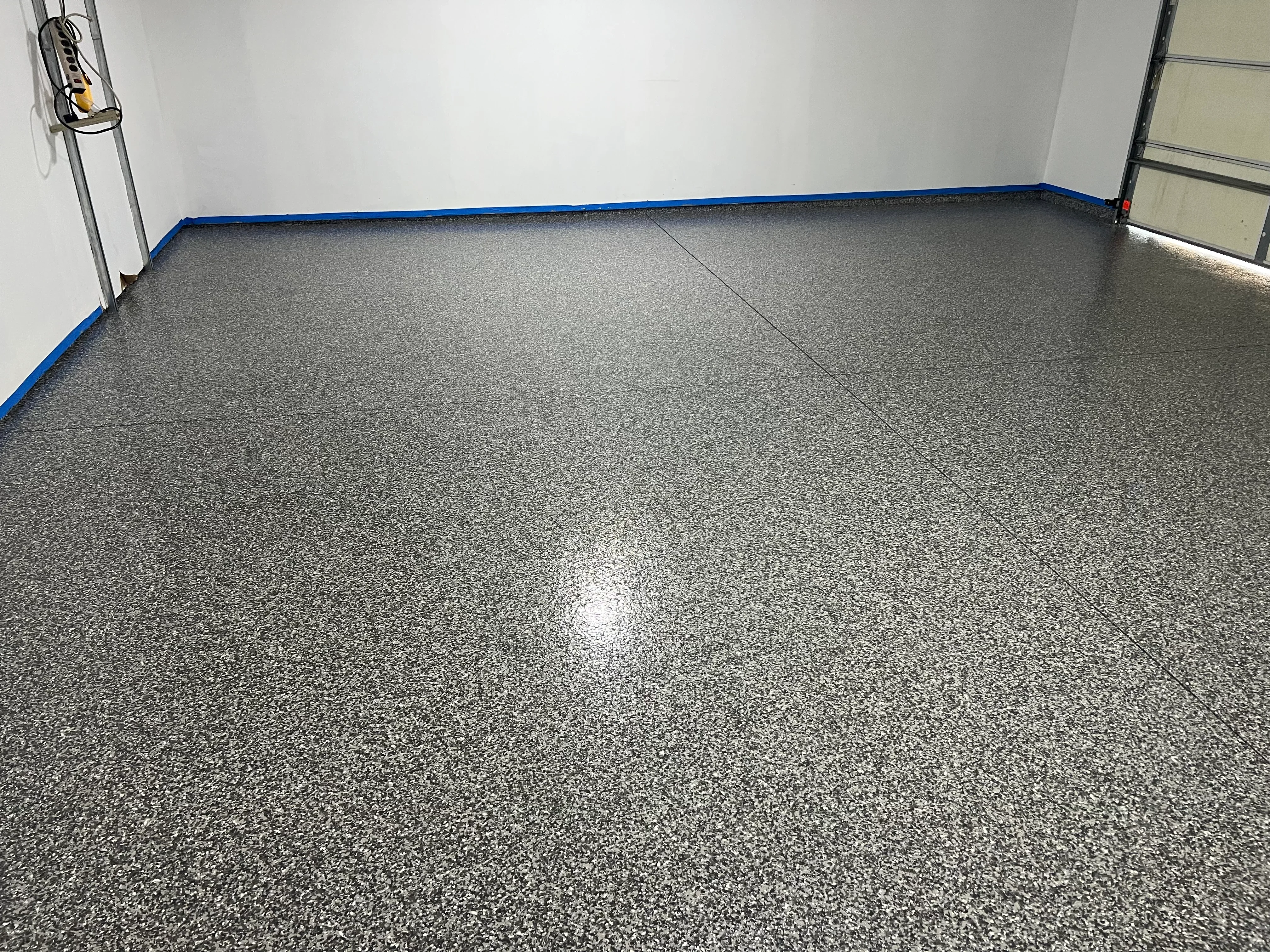 Charcoal gray epoxy-coated garage floor with speckled finish and blue trim