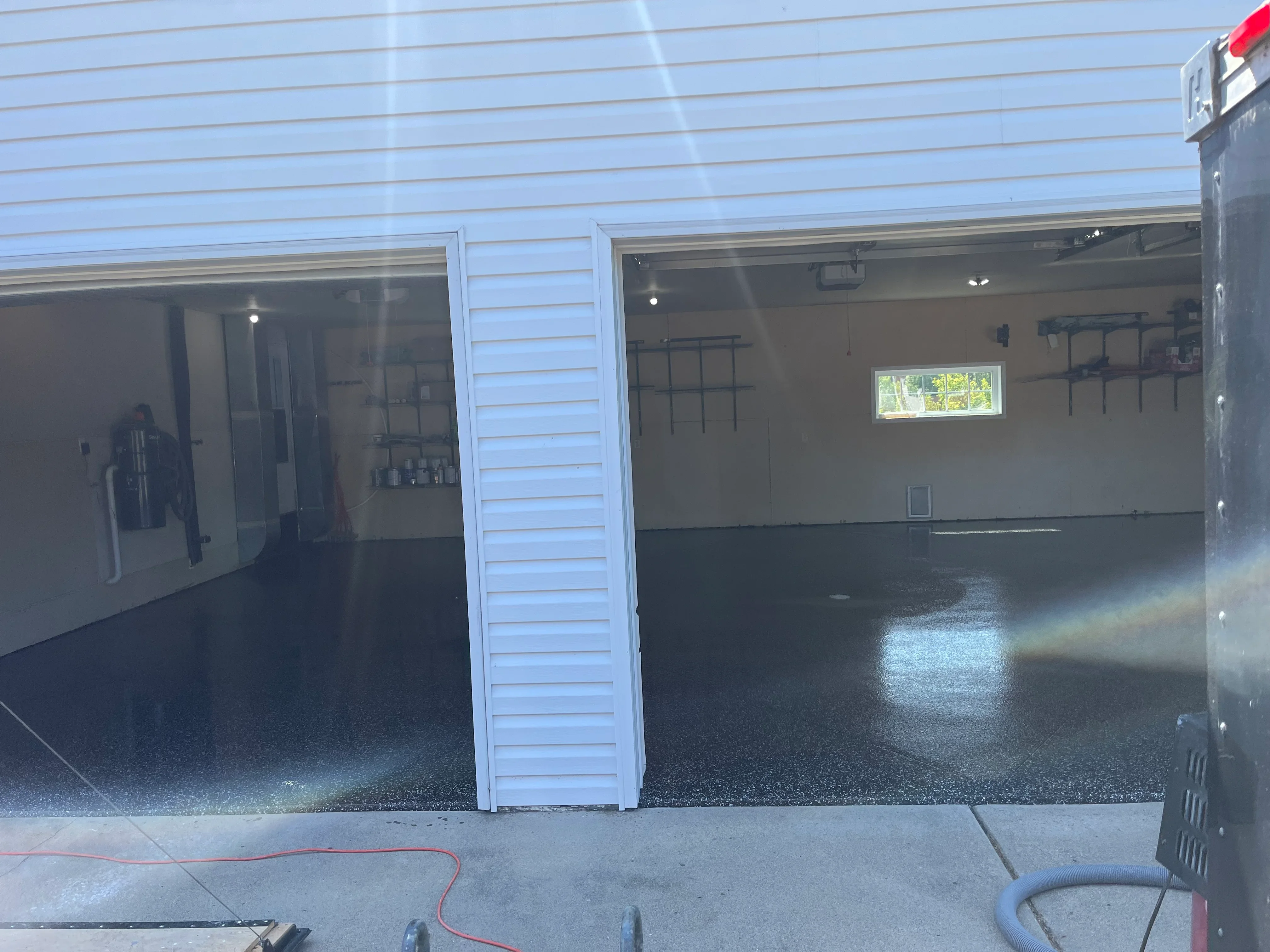 Garage floor with dark epoxy coating and speckled aggregate finish, newly applied