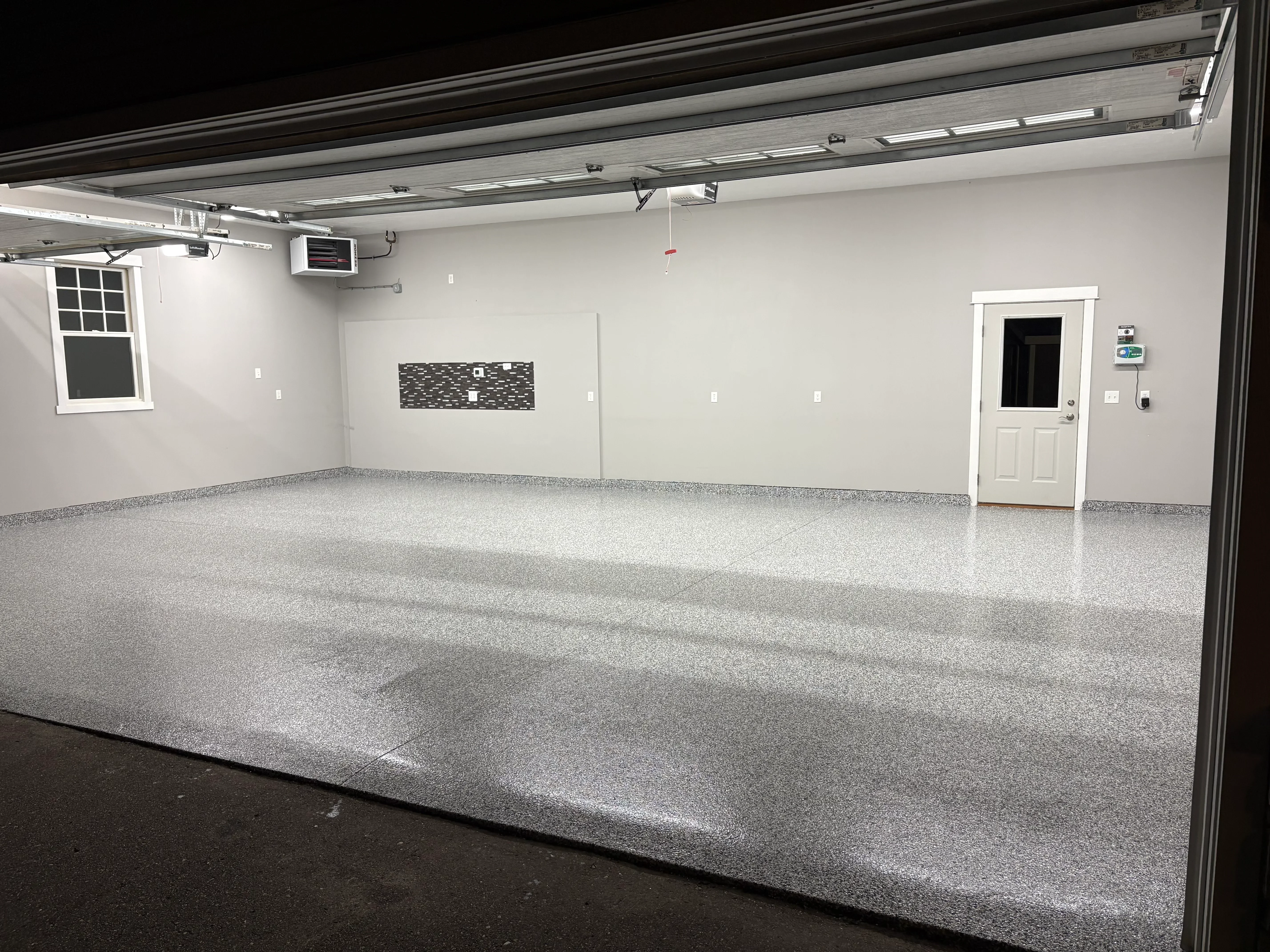 Light gray speckled epoxy-coated garage floor with white walls and overhead door